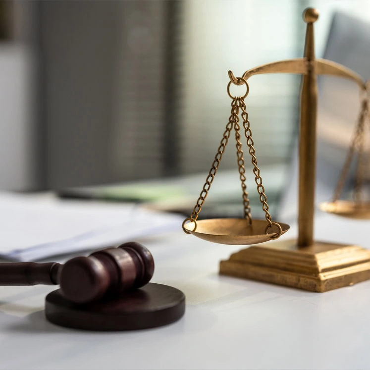 A wooden judge’s gavel rests beside a brass balance scale on a desk, symbolizing the work of a civil law attorney and the pursuit of justice.