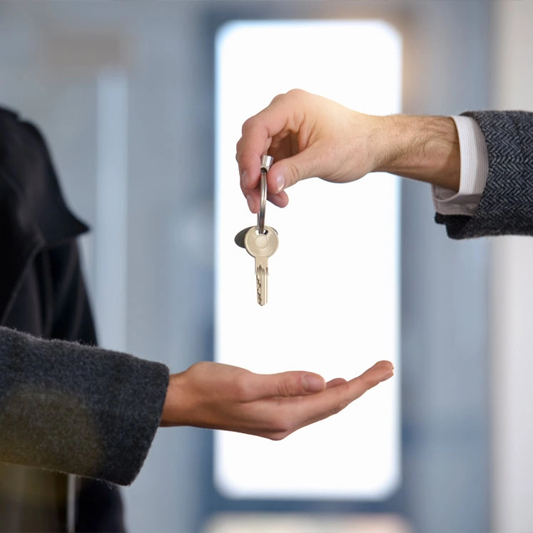A person hands over a set of keys to another, both in dark coats—an exchange that might follow guidance from a civil law attorney.